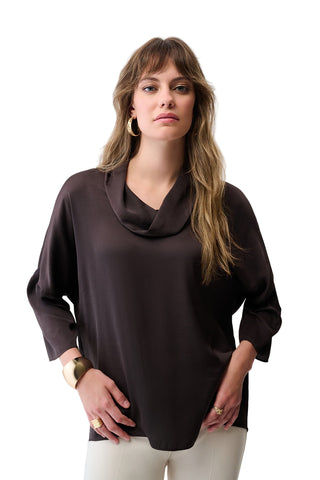 Woman wearing a brown cowl-neck top against a white background