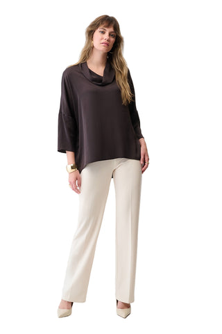 Woman wearing a dark brown top and white pants on a white background