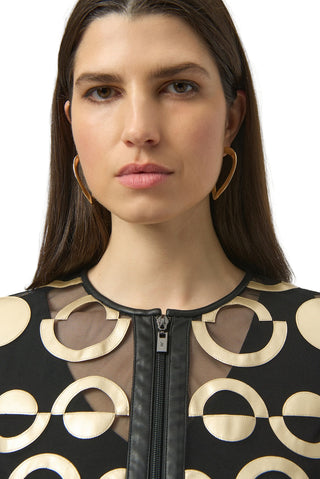 Woman wearing a black and gold patterned top with a plain background