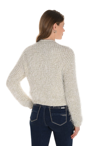 Woman wearing a textured beige sweater and dark jeans on a white background