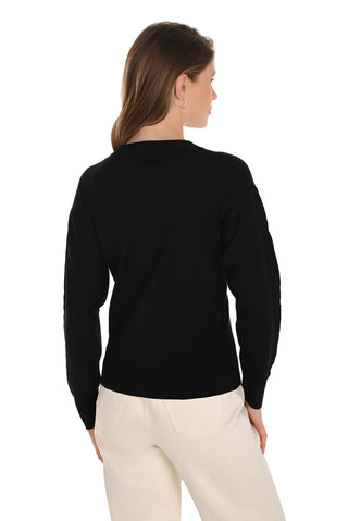 Woman wearing a black long-sleeve top and white pants on a white background
