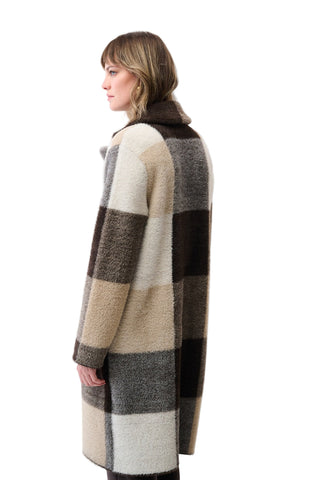 Woman wearing a long, checkered coat on a white background