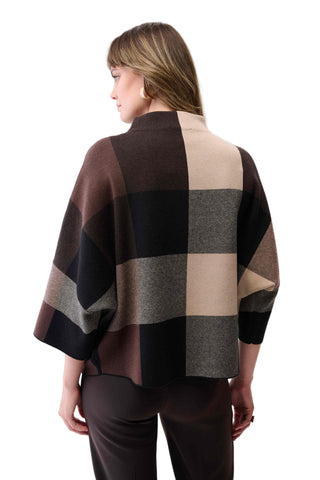 Woman wearing a checkered poncho with a neutral background