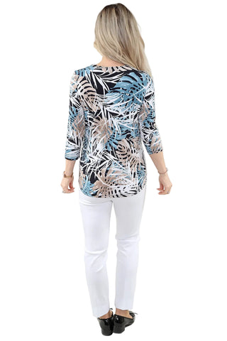 Woman wearing a patterned top and white pants on a plain background