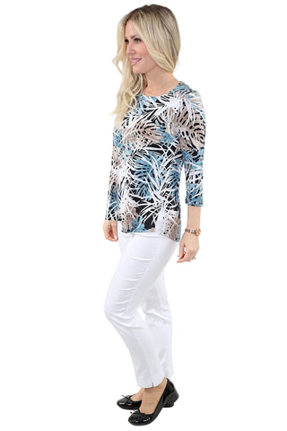 Woman wearing a patterned top and white pants on a plain background