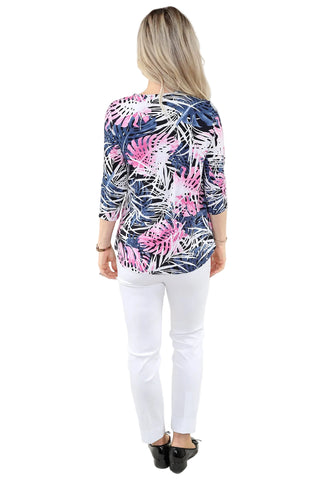 Woman wearing a colorful floral blouse and white pants on a plain background