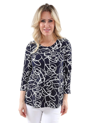 Woman wearing a navy blue top with white abstract pattern on a plain background