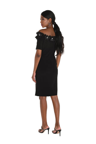Woman wearing a black off-shoulder dress with floral details on a white background