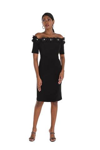 Woman wearing a black off-shoulder dress with embellishments on a white background
