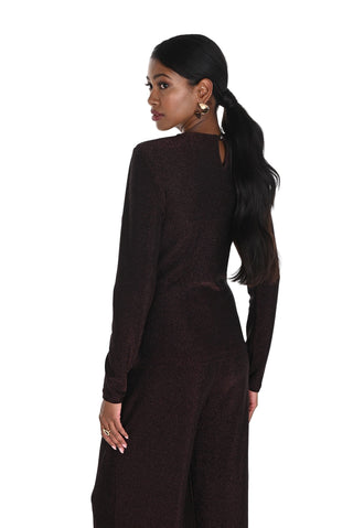 Woman wearing a dark brown long-sleeve top and wide-leg pants on a white background