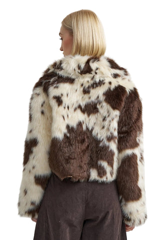 Person wearing a brown and white patterned fur coat on a plain background
