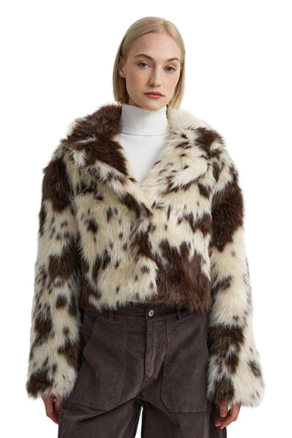 Person wearing a brown and white fur coat on a plain background