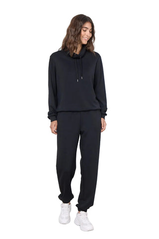 Woman wearing navy outfit and white sneakers against white background