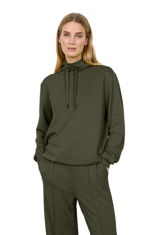 A woman modeling an olive green pullover hoodie and matching wide-leg sweatpants against a plain white studio background.