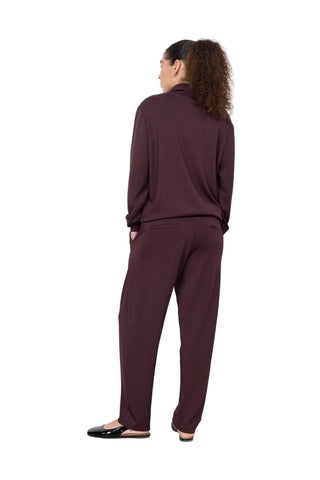 Person wearing a burgundy outfit standing against a white wall