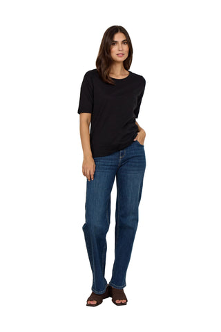 Woman wearing a black top and blue jeans against a white background