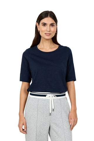 Woman wearing a navy blue top and gray pants on a white background