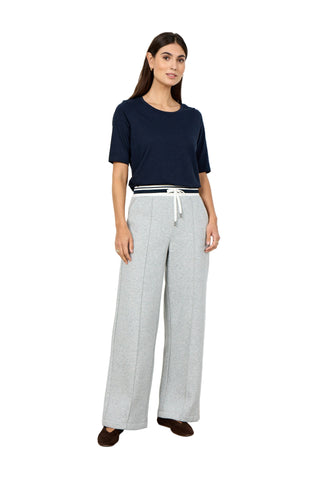 Woman wearing a navy top and gray plaid pants on a white background