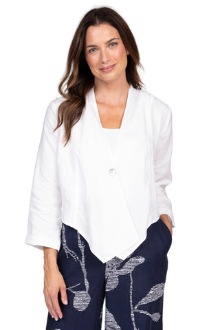 Woman wearing a white blouse and navy pants with a white pattern on a plain background