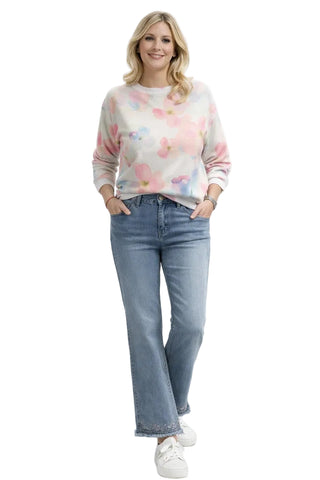 Woman wearing a colorful sweater and light blue jeans on a white background