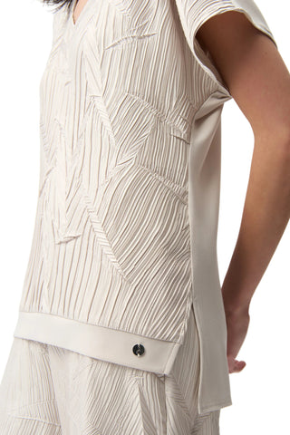 Close-up of a person wearing a beige patterned outfit on a white background