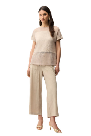 Woman wearing a beige top and pants on a white background