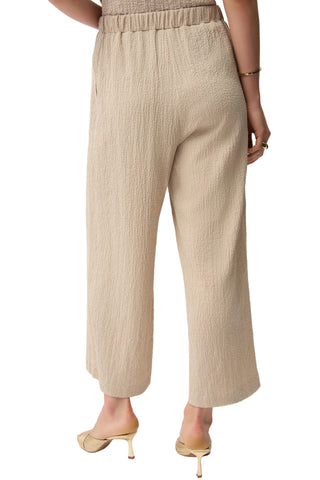 Beige textured pants worn by a person on a white background