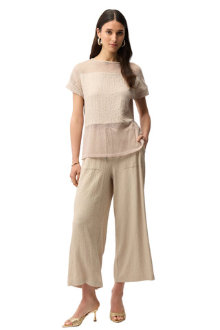Woman wearing a light pink top and beige pants on a white background