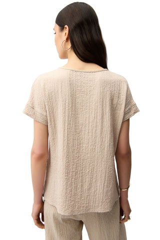 Woman wearing a beige textured top and pants on a white background
