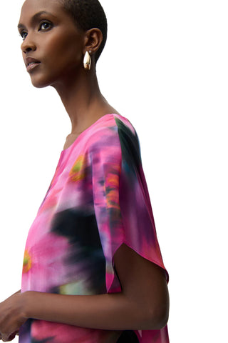 Woman wearing a colorful tie-dye top against a white background