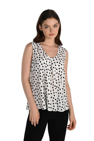 Woman wearing a sleeveless polka dot top against a plain background