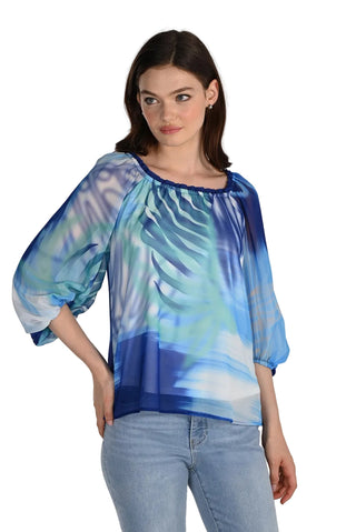 Woman wearing a blue and green patterned blouse with jeans on a white background