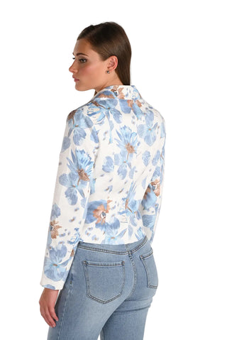 Woman wearing a floral blouse and jeans on a plain background