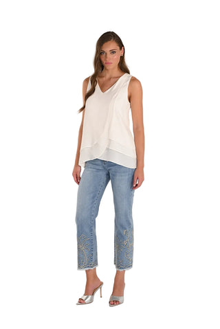 Woman wearing a white sleeveless top and light blue jeans with a white background