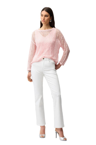 Woman wearing a pink knitted sweater and white pants on a white background
