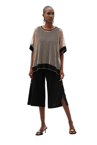 Woman wearing a patterned top and black culottes on a white background