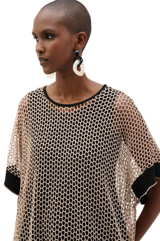 Woman wearing a sheer black and white patterned top on a plain background
