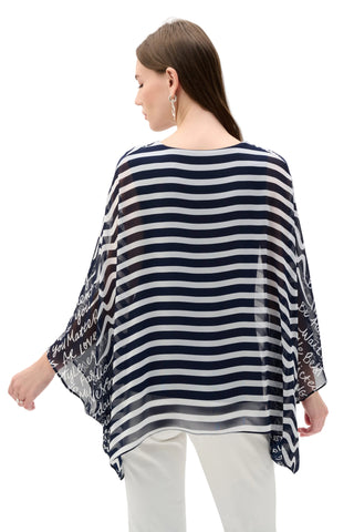 Woman wearing a navy and white striped poncho with floral embroidery on a white background