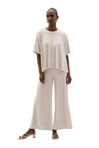 Woman wearing a white top and wide-leg pants on a white background