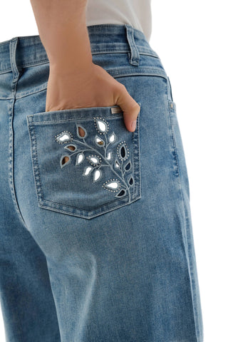 Close-up of blue jeans with floral embroidery on the pocket against a white background
