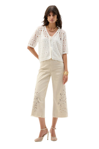 Woman wearing a white lace top and beige pants on a white background