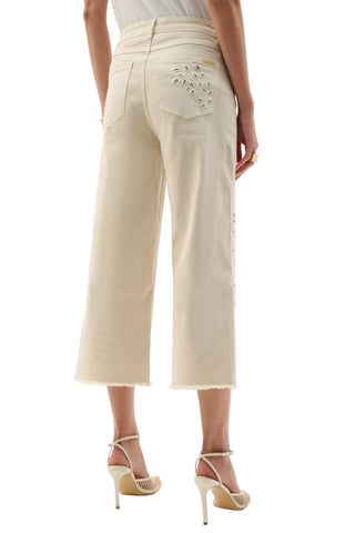 Person wearing beige pants with floral embroidery on a white background