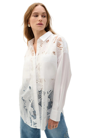 Woman wearing a white lace-trimmed shirt with a patterned design on a white background
