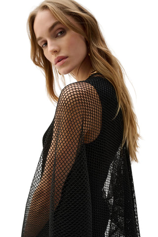 Woman wearing a black fishnet top against a white background