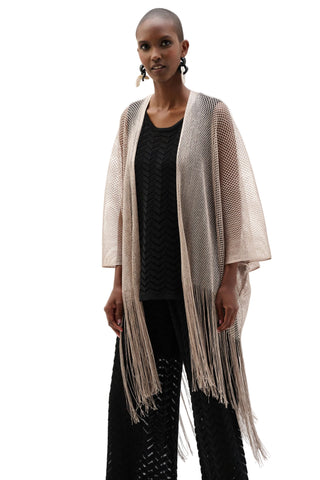 Woman wearing a beige fringe cardigan over a black top and pants on a white background