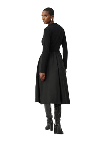 Woman wearing a black dress with long sleeves and a white background