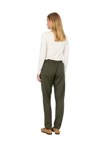 Woman wearing a white top and green pants against a white background