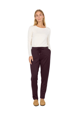 Woman wearing a white sweater and dark pants against a white background