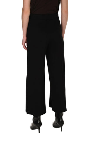 A model shown from the back wearing black wide-leg cropped trousers, a dark brown sleeveless top, and black high-heeled boots against a plain white studio background.