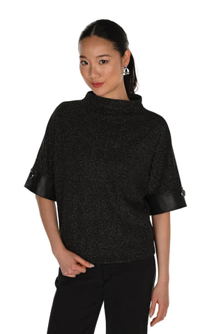 Woman wearing a black poncho with leather cuffs on a white background